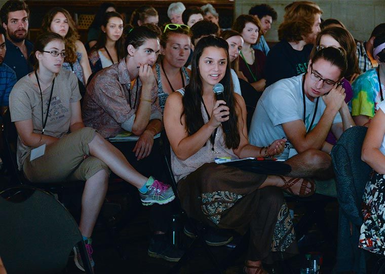 Members of the audience at a Power Shift convergence ask a question and listen thoughtfully in a darkened room.